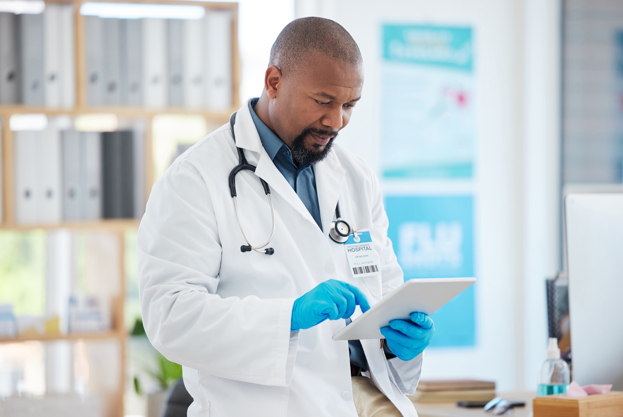 Focused doctor using a digital tablet in his clinic office. African american specialist using an on